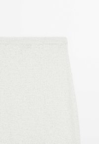 Tessuto a maglia grigio chiaro con una consistenza morbida, caratterizzato da un design senza cuciture e una forma leggermente affusolata. Aspetto minimalista e versatile.