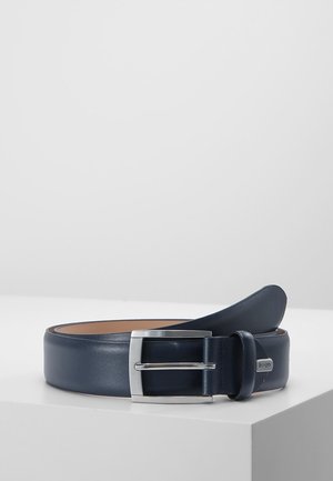 Coiled navy blue leather belt with silver rectangular buckle and small metal tag on loop, placed on white surface against light gray background.