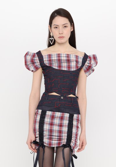Denim and plaid crop top with puff sleeves, featuring red stitching and cutout details; paired with a plaid ruched mini skirt with ribbons.
