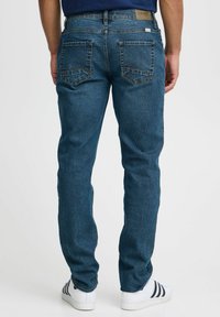 Vaqueros de mezclilla azul con un corte recto, que cuentan con dos bolsillos traseros con detalles de costura y una etiqueta de marca en la cintura.