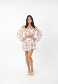 Crop top beige off-shoulder con strisce zebra bianche, maniche a palloncino, abbinato a una gonna avvolgente coordinata con orlo arricciato.