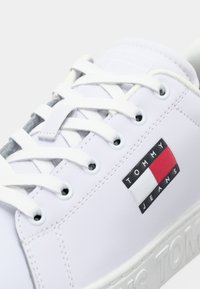 Baskets Tommy Jeans blanches avec des lacets blancs, patch logo sur le côté et logo en relief sur la semelle épaisse.