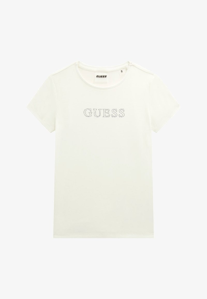 Balta trumpa rankovėmis marškinėliai, pagaminti iš medvilnės, su apykakle ir „GUESS“ logotipu, dekoruotu kristalais. Yra paprasta, lygi tekstūra.