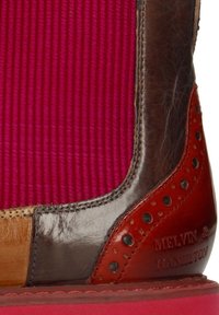 Botte en cuir multicolore avec panneau élastique bordeaux et détails perforés, avec "Melvin & Hamilton" embossé sur le talon.
