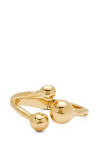 Bague en métal doré avec un design ouvert et deux accents sphériques à chaque extrémité. Surface lisse et réfléchissante ; forme moderne et minimaliste.
