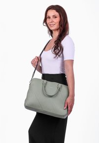 Grüne Leder-Handtasche mit diagonaler Naht, doppelten Traggriffen und einem abnehmbaren Schulterriemen. Glatte Oberfläche mit dezentem Markenlogo.