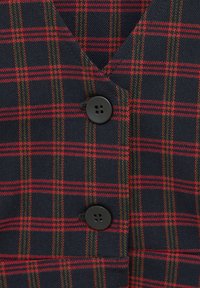 Gilet en tissu navy avec un motif à carreaux rouge et vert. Pr ésente un col en V et deux boutons noirs à quatre trous à l'avant.