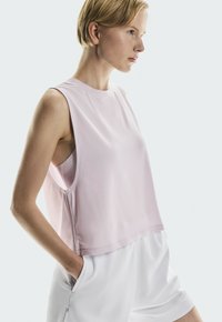 Mouwloos sporttop in lichtroze, met een losse pasvorm, ronde hals en diepe armsgaten, gemaakt van zachte, ademende stof.