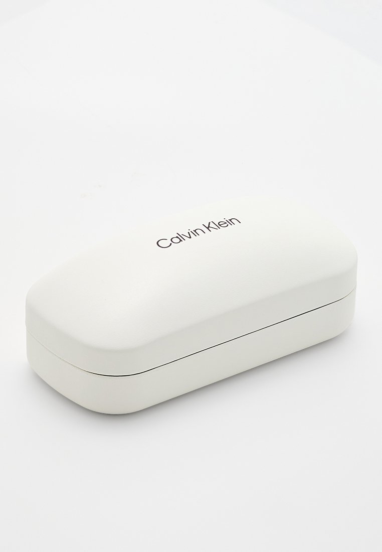 Biały twardy etui na okulary o gładkiej fakturze, zaokrąglonym kształcie i wytłoczonym logo "Calvin Klein" na górze.