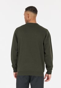 Sweatshirt vert olive en matériau doux, avec un col rond, des manches longues et des poignets et ourlets côtelés. Design minimaliste.