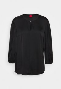 Blouse en satin noir avec un col rond, un détail en forme de trou de serrure et des manches ballons. Présente une poche latérale discrète et une coupe ample.