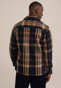 Marineblauwe en tan geruite flanellen shirt met kraag, lange mouwen en knoopsluitingen; zachte textuur met een ontspannen pasvorm.