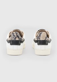 Weiße Sneaker mit einem schwarzen Akzent und Python-Print an der Ferse. Obermaterial aus glattem Leder mit strukturiertem Rückenteil. Gummisohle.