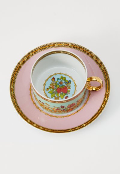 Porzellantasse mit goldenem Griff und floralem Schmetterlingsdesign im Inneren, platziert auf einem rosa Teller mit verziertem goldenen und blumigem Rand.