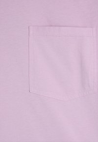 Vaalean violetti puuvillakangas, jossa on räätälöity tasku suorin ompelein. Pehmeä rakenne ja sileä pinta.