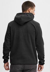 Zwarte hoodie gemaakt van zachte fleece. Heeft een relaxte pasvorm, lange mouwen en ribgebreide boorden. Geen zichtbaar logo of patronen.