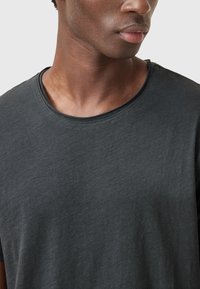 Mørkegrå bomulds-T-shirt med rund halsudskæring, korte ærmer og en blød tekstur, der viser diskret syninger omkring halsudskæringen.