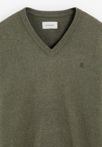 Suéter de mezcla de algodón verde con diseño de cuello en V, cuello acanalado y un pequeño logo en el lado izquierdo del pecho. Textura suave con un acabado liso.