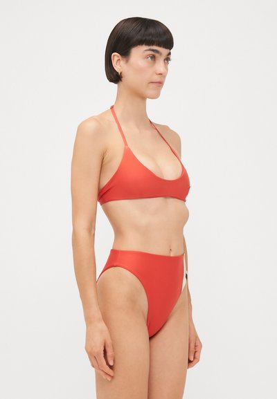 Sarkans bikini komplekts ar trīsstūrveida augšdaļu un augsto jostasvietu apakšdaļu. Izgatavots no gludas auduma, ar regulējamiem siksnām un minimālistisku dizainu.