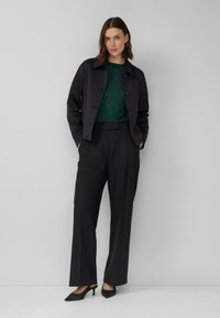 Czarna krótka kurtka z guzikami, zielona koszula ozdobiona subtelnymi brokatami oraz czarne spodnie z wysokim stanem. Całość uzupełniają eleganckie czarne szpilki.
