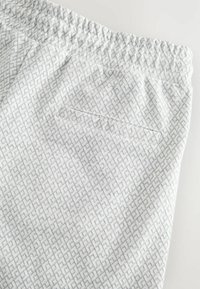 Lichtgrijze broek met een geometrisch patroon, elastische tailleband en een enkele achterzak met een zachte textuur.