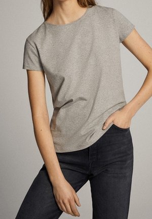 Gray short-sleeve t-shirt made of soft fabric, featuring a round neck and relaxed fit, paired with dark jeans. Simple design with no patterns.