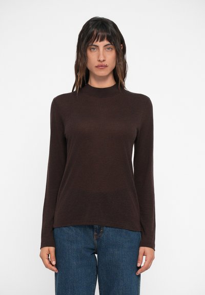 Top marrón de manga larga con cuello alto y un corte relajado, combinado con jeans de mezclilla azul. La tela tiene una textura suave.