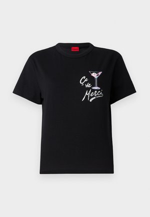 Svart bomull t-skjorte med korte ermer, har et hvitt og rosa grafisk bilde av et martiniglass og teksten "Ça va Merci" i en leken skrifttype.