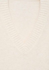 Cremefarbener V-Ausschnitt-Pullover, hergestellt aus weichem Material mit gerippten Details entlang des Ausschnitts. Verfügt über eine glatte, gleichmäßige Textur.
