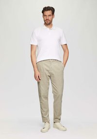 Witte polo shirt, beige gestreepte broek, crèmekleurige sneakers. Klassieke pasvorm, rechte pijpen, minimalistisch design, katoenen materiaal zonder zichtbare patronen.