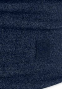 Navy felt hat with a smooth texture, featuring a dark leather logo patch. Round design with a soft, cozy appearance.