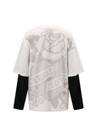 Overmaat t-shirt met korte mouwen in het wit met zwarte lange mouwen. Bevat een grijze rozenafbeelding en de tekst "ETERNALE LIEFDE" op de rug.