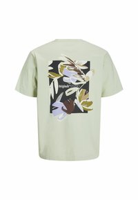 Light green cotton t-shirt featuring a vibrant floral graphic in shades of purple, black, and brown, with "Originals STUDIO" text integrated.