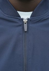 Ναυτικό τζάκετ με φερμουάρ και υφή στον γιακά. Διαθέτει κεντρικό φερμουάρ, κομψό σχεδιασμό και πλεκτό υπόστρωμα σε ανοιχτό μπλε χρώμα.