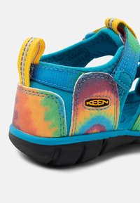 Keen barnesandal med multicolor tie-dye overdel, blå stropper og en teksturert svart gummisåle for godt grep.