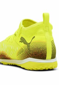 Žltá textilná topánka so sieťovaným zvrškom, s čiernymi pruhmi a logom Puma na boku. Štruktúrovaná podrážka pre lepšiu priľnavosť.