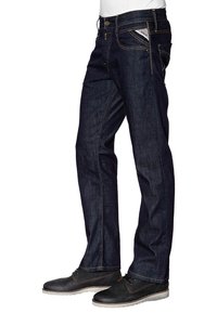 Jeans de mezclilla azul oscuro con un corte clásico, que presentan costuras amarillas, cinco bolsillos y una pequeña etiqueta de logo roja cerca de la cintura.