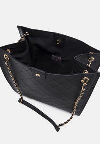 Black quilted tote bag made of synthetic material with gold hardware, chain accent strap, and an open compartment design.