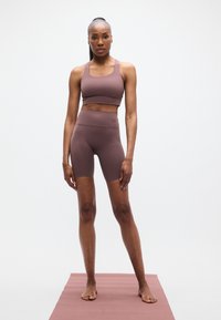Σετ με μπορντό αθλητικό σουτιέν και σορτς με ψηλή μέση. Λείο, ελαστικό ύφασμα με μινιμαλιστικό σχέδιο, χωρίς ορατά λογότυπα ή μοτίβα.