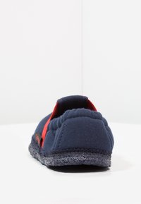 Marine canvas pantoffel met een gestructureerde donkere zool, een rode accentband en een gevoerde enkel voor comfort.