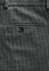 Gray pinstriped fabric featuring a front pocket with a black button. The texture is smooth with fine vertical lines.