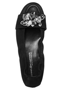 Chaussure plate noire avec des côtés élastiques et une grande décoration en pierre facettée transparente sur la bride avant.