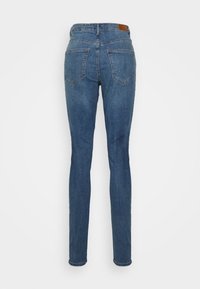 Jeans de denim azul skinny com uma cintura de altura média, dois bolsos traseiros e um patch de couro castanho da marca na parte traseira da cintura.