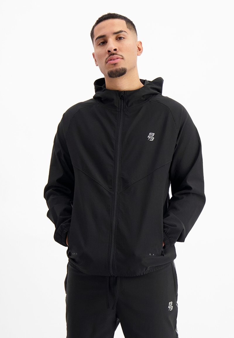 Zwarte lichtgewicht zip-up jack met capuchon, voorzien van een subtiele logo, elastische manchetten en een ontspannen pasvorm. Soepele textuur en minimaal ontwerp.