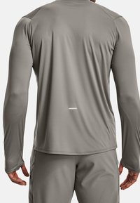 Langärmliges Sportshirt in Hellgrau, hergestellt aus glattem, dehnbarem Stoff mit flachen Nähten und einem reflektierenden Akzent am hinteren Saum.
