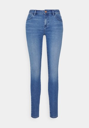 Blå skinny jeans med hög midja, framfickor och knäppning med knappar, visade mot en vit bakgrund.