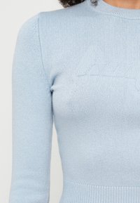 Απαλή μπλέ φούτερ μπλούζα με rib ύφανση, στρογγυλή λαιμόκοψη και μακριά μανίκια. Διαθέτει διακριτές ανάγλυφες λεπτομέρειες στην περιοχή του στήθους.