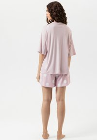 Haut rose à manches courtes en tissu doux associé à un short rose clair orné de grands pois blancs, offrant une coupe et un design décontractés.