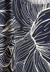 Tissu bleu avec de grands motifs de feuilles tropicales blanches en contour présentant des lignes de veines détaillées et des formes organiques.
