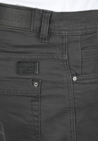 Grijze denim broek met een geborduurd merklabel, metalen details en een standaard ontwerp van zakken met verstevigde stiksels.